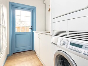 A laundry room with a blue door, a washing machine, and a drying rack. - 10 Person Holiday Home in Marstal (Marstal)