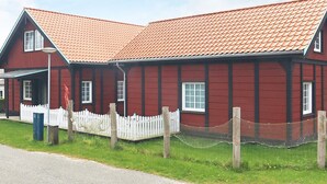 A red wooden building with a white picket fence and a red-tiled roof. - 10 Person Holiday Home in Marstal (Marstal)