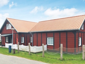 A red wooden building with a white picket fence and a red-tiled roof. - 10 Person Holiday Home in Marstal (Marstal)