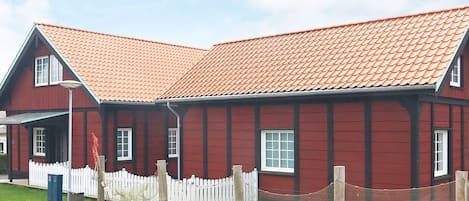 A red wooden building with a white picket fence and a red-tiled roof.