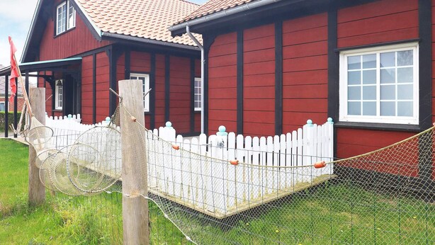 A red wooden house with a white picket fence and a metal gate. - 10 Person Holiday Home in Marstal (Marstal)
