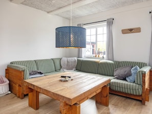 A cozy living room with a wooden table, striped green sofa, and a blue patterned hanging light fixture. - 10 Person Holiday Home in Marstal (Marstal)