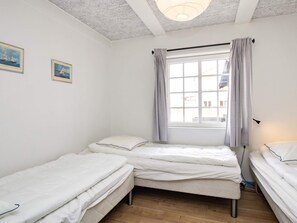 A room with two single beds, a window with curtains, and a ceiling light fixture. - 10 Person Holiday Home in Marstal (Marstal)