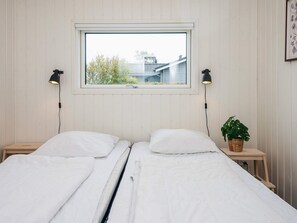 A double bed with white linens, two bedside lamps, a window with a view of a building, and a potted plant on a bedside table. - 6 Person Holiday Home in Ronde (Ronde)