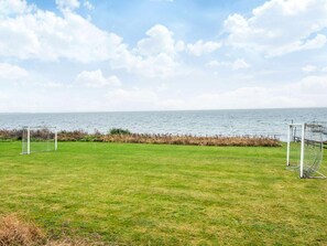 A grassy field with two soccer goals and a view of the sea.