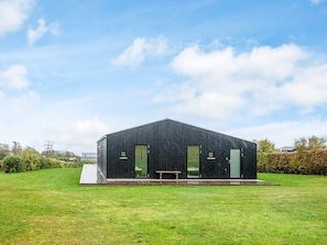 A modern building with a flat roof, large windows, and a wooden bench outside. - 6 Person Holiday Home in Ronde (Ronde)