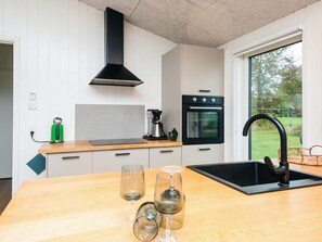 A modern kitchen with a built-in oven, a coffee machine, and a sink with a black faucet. - 6 Person Holiday Home in Ronde (Ronde)