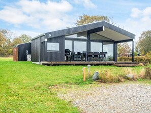A modern, single-story building with a covered outdoor seating area, large windows, and a number '9' sign. - 6 Person Holiday Home in Ronde (Ronde)