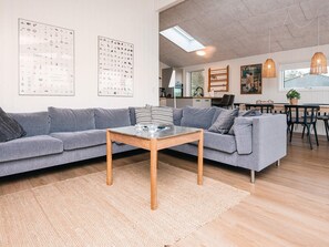 A modern living room with a grey sectional sofa, a wooden coffee table, and a large window with a view. - 6 Person Holiday Home in Ronde (Ronde)