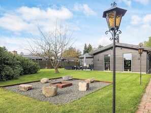 A modern house with a patio area featuring a fire pit, outdoor furniture, and a decorative lamp post. - 4 Star Holiday Home in Vaeggerlose (Vaeggerlose)