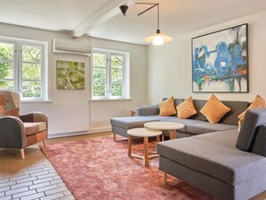 A living room with a grey sofa, a round coffee table, and a large abstract painting on the wall. - 14 Person Holiday Home in Ronne (Akirkeby)
