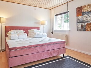 A bedroom with a pink bed, white bedding, a radiator, a window, and a painting on the wall. - 14 Person Holiday Home in Ronne (Akirkeby)