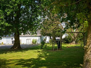 Un quartier résidentiel avec un grand arbre, une balançoire et une maison blanche avec un garage.