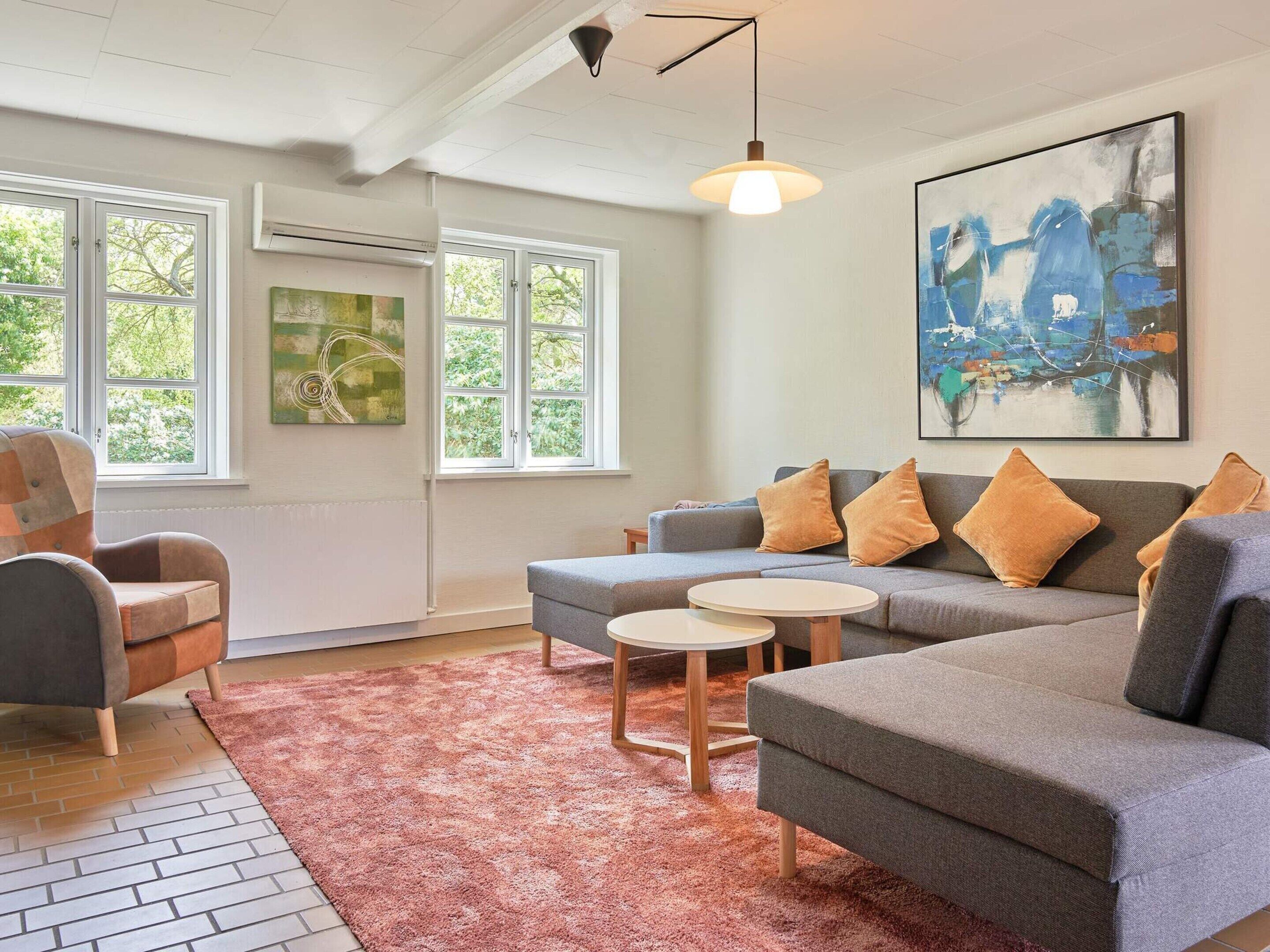 A living room with a grey sofa, two armchairs, a coffee table, and a large abstract painting.