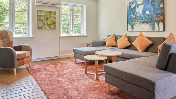 A living room with a grey sofa, two armchairs, a coffee table, and a large abstract painting. - 14 Person Holiday Home in Ronne (Akirkeby)