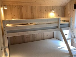 Habitación con literas, paredes de madera y una escalera.