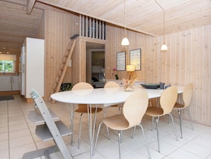 A dining area with a round table, six chairs, a ladder, and a kitchen in the background. - 6 Person Holiday Home in Oksbol (Oksbol)