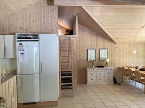 A compact kitchen with a white refrigerator, wooden cabinets, and a dining area with a table and chairs.