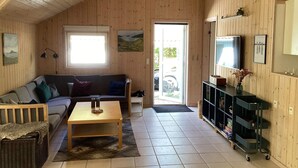 Un intérieur chaleureux, avec des murs en bois, un canapé, une table basse et un téléviseur fixé au mur.