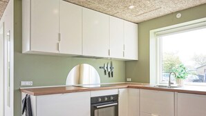 A kitchen with white cabinets, a wooden countertop, a built-in oven, and a window with a view of the outside.