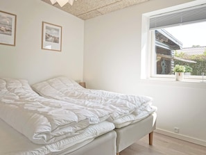 A bedroom with a bed, a window with a view of a building, and two framed pictures on the wall. - 4 Star Holiday Home in Ronne (Ronne)