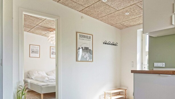 Un dormitorio moderno y minimalista con cama, un banco de madera y un cuadro enmarcado en la pared.