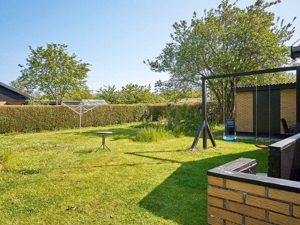 A backyard with a swing set, a small table, and a brick wall.