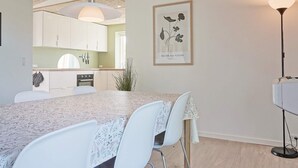 Una cocina moderna con armarios blancos, una isla grande y una lámpara colgante.