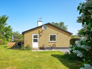 A single-story brick house with a white door, a satellite dish, and a small window.