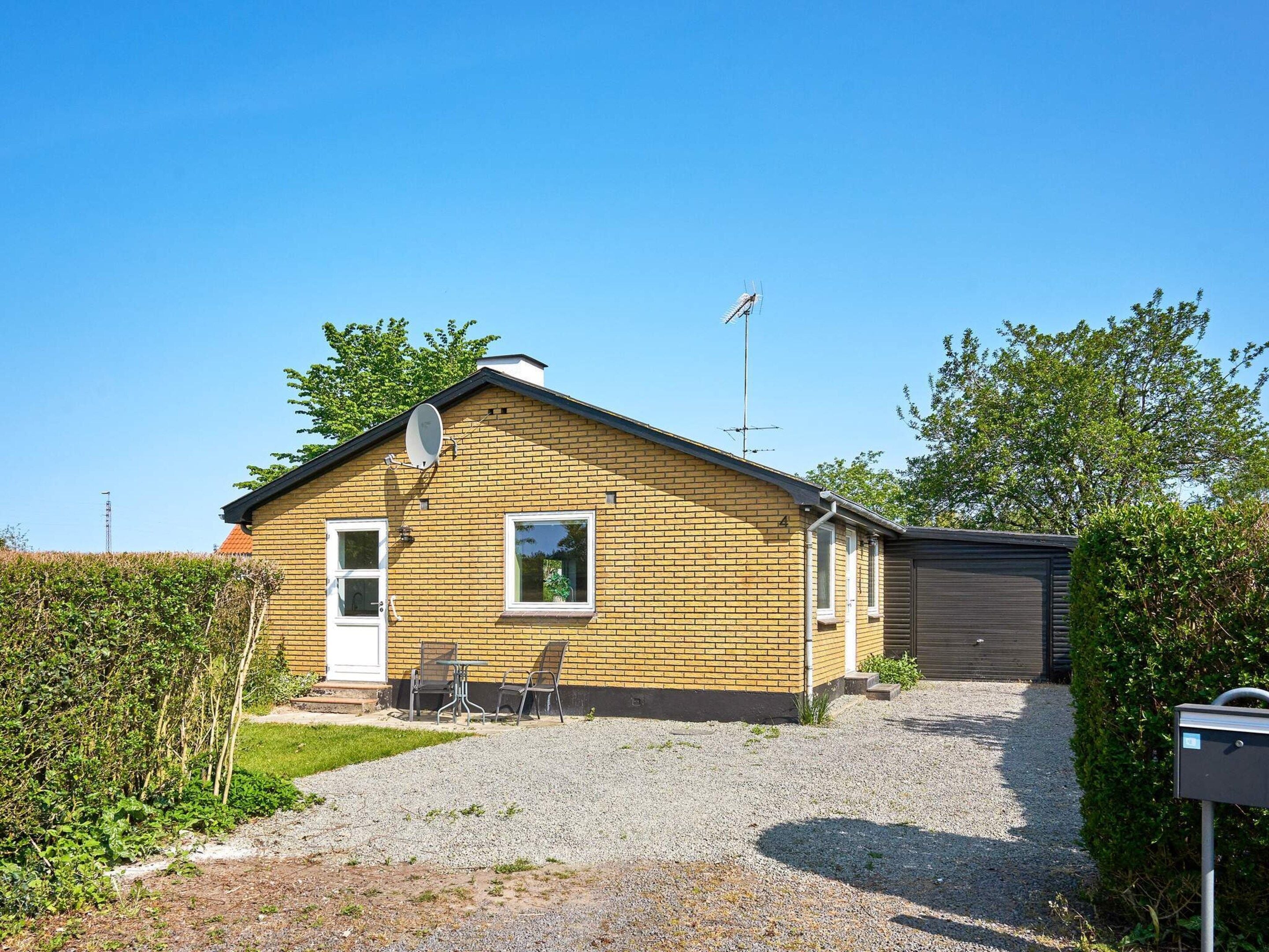 A single-story brick house with a satellite dish, a garage, and a gravel driveway.