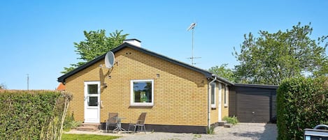 A single-story brick house with a satellite dish, a garage, and a gravel driveway.