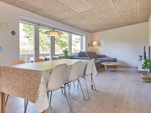 Un espai de estar modern amb zona de menjador, sofà i una finestra gran que deixa entrar llum natural.