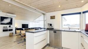 A modern kitchen with a dishwasher, a coffee machine, and a large window providing a view. - 6 Person Holiday Home in Vaeggerlose (Vaeggerlose)