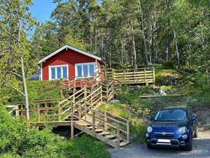 A red cabin with wooden stairs leading to a deck, surrounded by forest. - 4 Star Holiday Home in Varmdo (Fågelbrolandet)