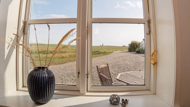 A window with a view of a gravel path and a chair outside. - 6 Person Holiday Home in Lemvig (Lemvig)
