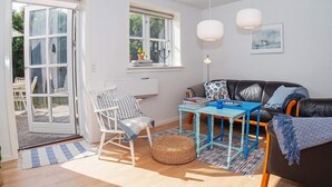 A bright living room with a sofa, a table, a chair, and a large window. - 6 Person Holiday Home in Lemvig (Lemvig)