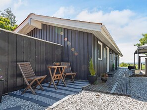 A wooden deck with a table and chairs, a potted plant, and a view of the ocean. - 7 Person Holiday Home in Hojslev (Hojslev)