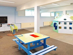 A playroom with a blue table, a toy horse, and a house play structure.
