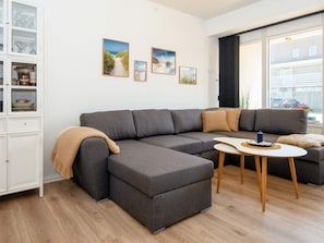 A modern living room with a grey sectional sofa, a small round coffee table, and a cabinet with glass doors.