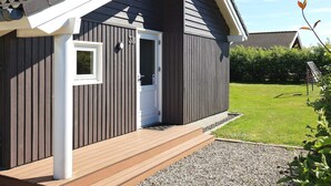 A modern building with a dark exterior, a white door, and a small window. - 6 Person Holiday Home in Vaeggerlose (Vaeggerlose)