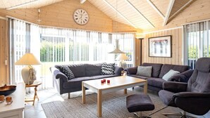 A spacious living area with a wooden ceiling, a large clock, and a modern sofa set. - 6 Person Holiday Home in Vaeggerlose (Vaeggerlose)