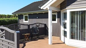 A wooden deck with a railing, a small table, and a chair. - 6 Person Holiday Home in Vaeggerlose (Vaeggerlose)