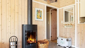 A room with a wood-burning stove, a wicker basket, a metal trash can, and a vintage-style chest of drawers. - 6 Person Holiday Home in Vaeggerlose (Vaeggerlose)