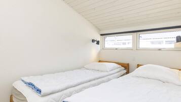 A room with two single beds, a window with a view, and a wall-mounted lamp.