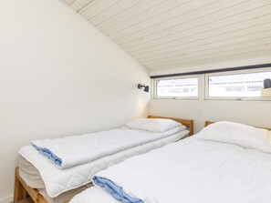 A room with two single beds, a window with a view, and a wall-mounted lamp. - 2 Person Holiday Home in Vejers Strand (Vejers Strand)