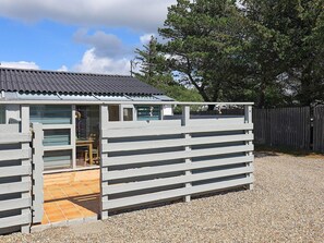 A small, single-story building with a tiled patio area and a wooden fence. - 2 Person Holiday Home in Vejers Strand (Vejers Strand)