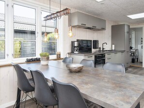 A modern kitchen with a central island, built-in appliances, and a dining area with chairs. - 6 Person Holiday Home in Bjert (Bjert)