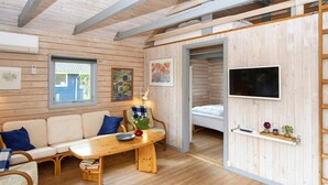 Um quarto aconchegante com piso de madeira, um sofá, uma mesa e uma cama.