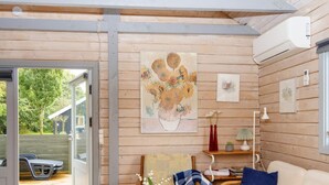 Um quarto acolhedor com decoração em madeira, um sofá, uma mesa com um vaso e uma pintura de girassóis.