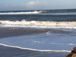 A beach with waves, a clear sky, and a distant buoy. - 6 Person Holiday Home in Fjerritslev (Fjerritslev)